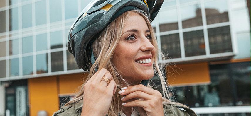 Femme s'accrochant un casque de vélo en souriant